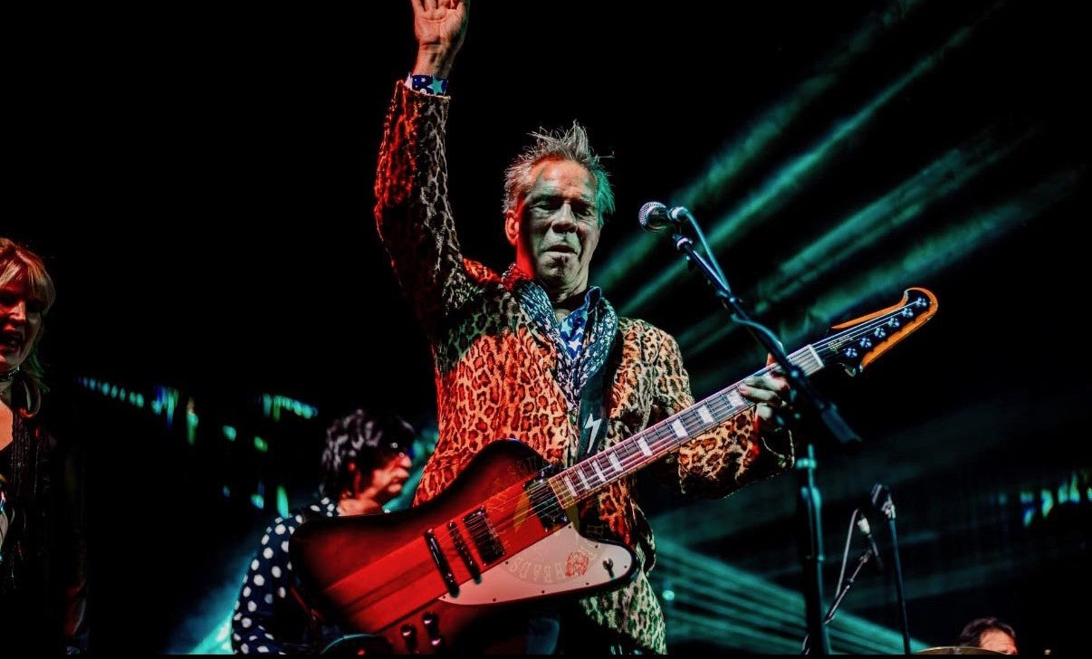 Andy Hilfiger performing on bass in a leopard-print jacket