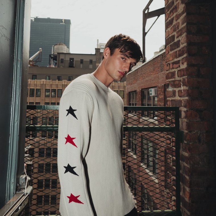 Men’s Star Crewneck Sweater in ivory, on a New York fire escape